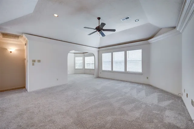 an empty room with windows and ceiling fan
