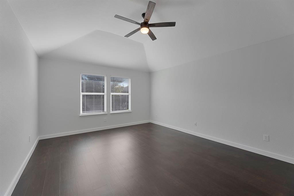 605 Clearbrook Street Azle, TX 76020 - Photo 15 of 33 Vaulted ceiling room featuring dark wood-finish flooring, two windows with blinds, a ceiling fan with integrated lighting, and neutral wall finishes