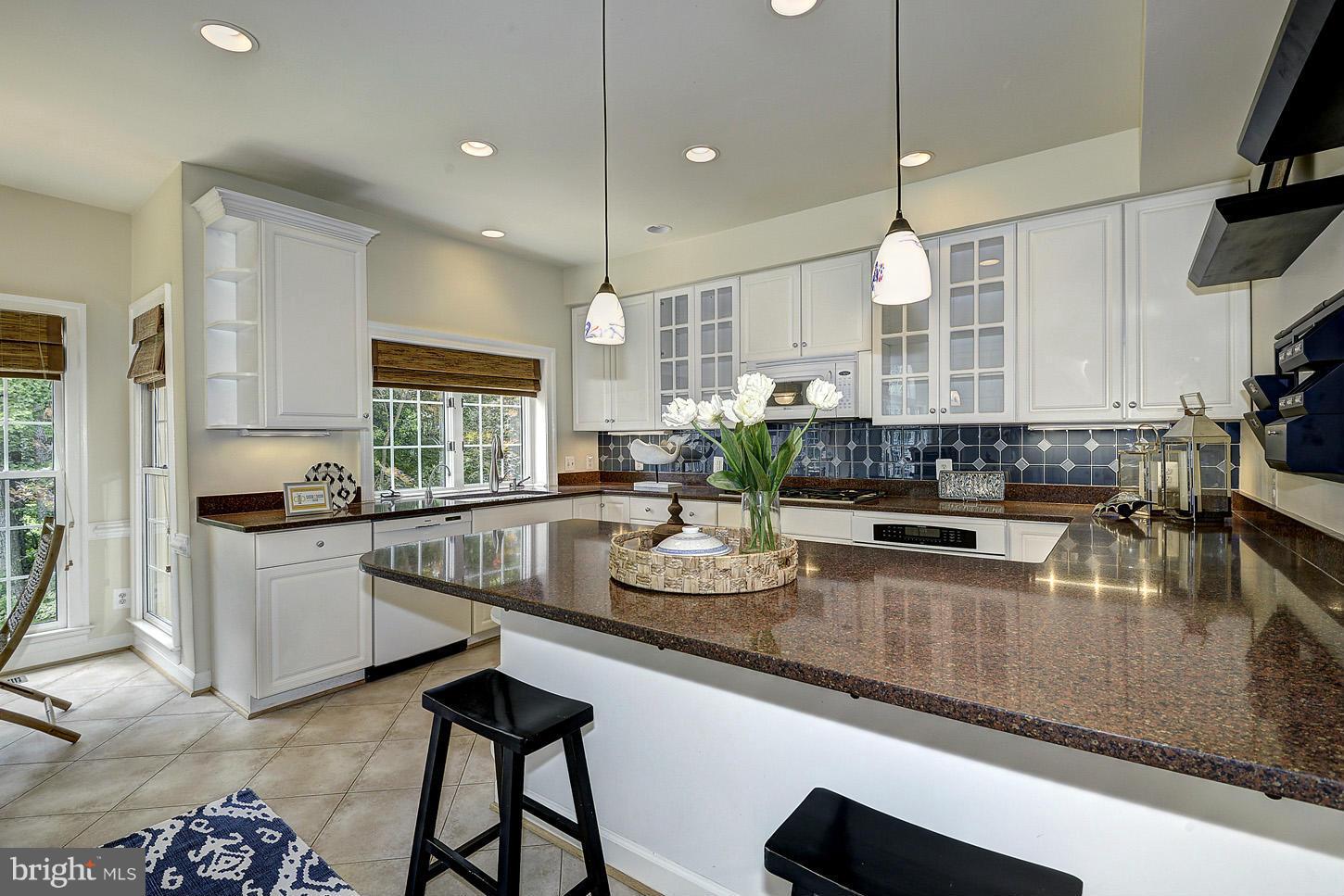 9730 Hidden Valley Road Vienna, VA 22181 - Photo 11 of 30 a kitchen with stainless steel appliances granite countertop a stove a sink a oven a dining table and chairs with wooden floor