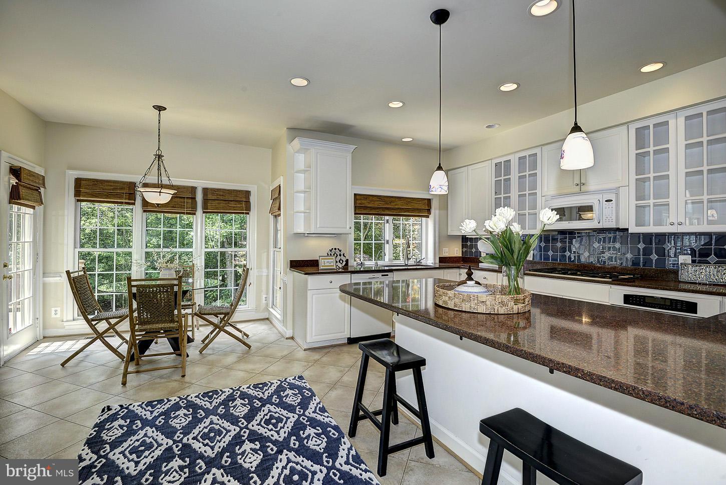 9730 Hidden Valley Road Vienna, VA 22181 - Photo 12 of 30 a kitchen with stainless steel appliances granite countertop a stove a sink a oven a dining table and chairs with wooden floor