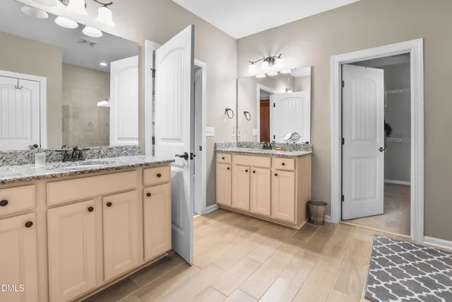 a spacious bathroom with a granite countertop sink a mirror and a shower