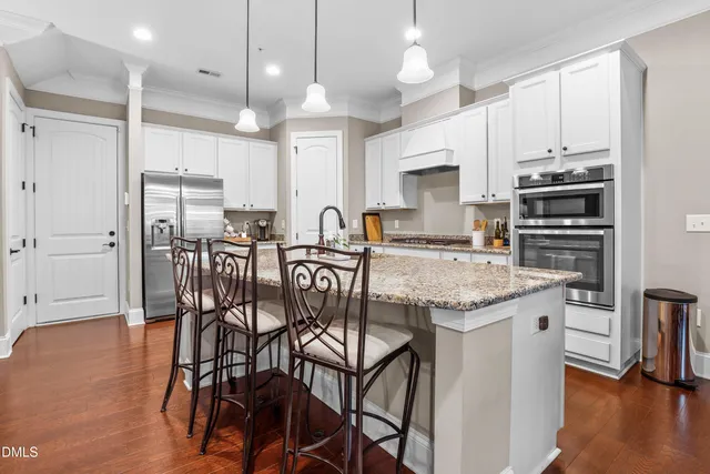 a kitchen with stainless steel appliances granite countertop a kitchen island a stove a table and chairs in it