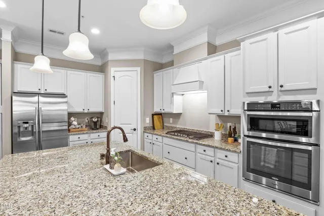 a kitchen with stainless steel appliances granite countertop a stove a sink and a refrigerator