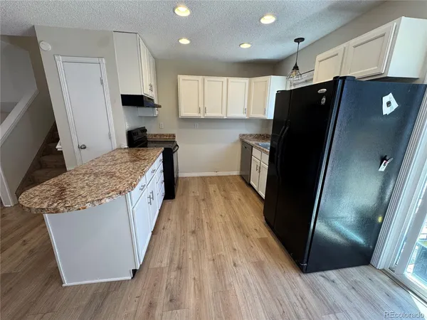 a kitchen with granite countertop a refrigerator a sink a stove and cabinets