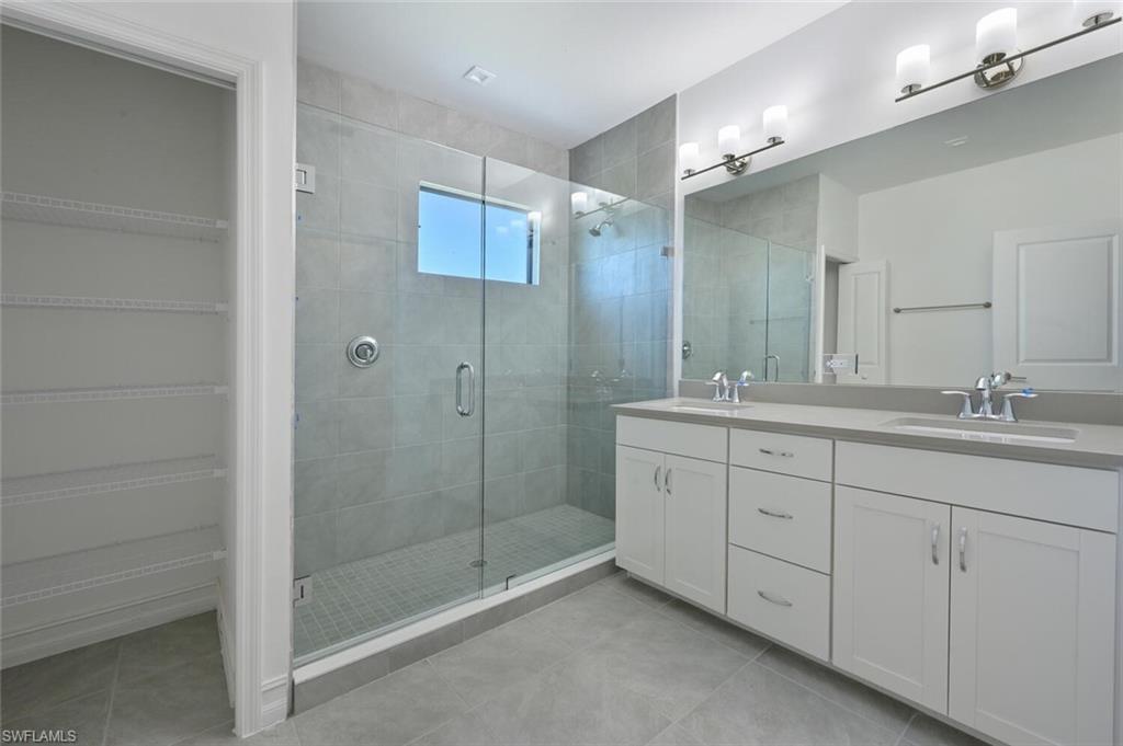 7611 Morgan Way Naples, FL 34119 - Photo 13 of 26 a bathroom with a shower sink and mirror