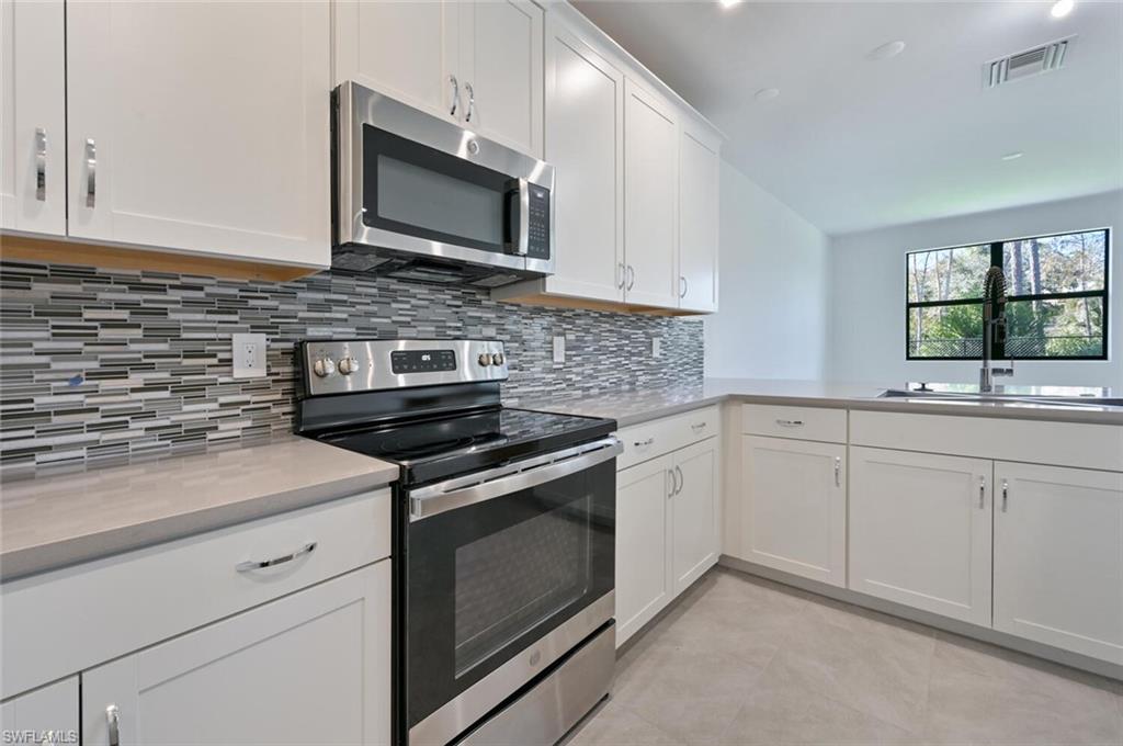7611 Morgan Way Naples, FL 34119 - Photo 7 of 26 a kitchen with white cabinets stainless steel appliances and sink