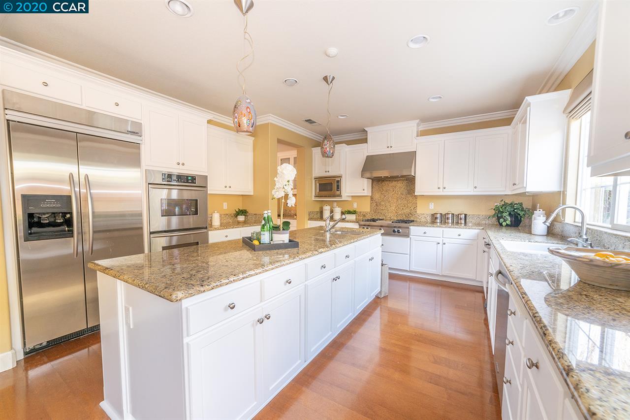 a large kitchen with kitchen island a large counter top stainless steel appliances and a window