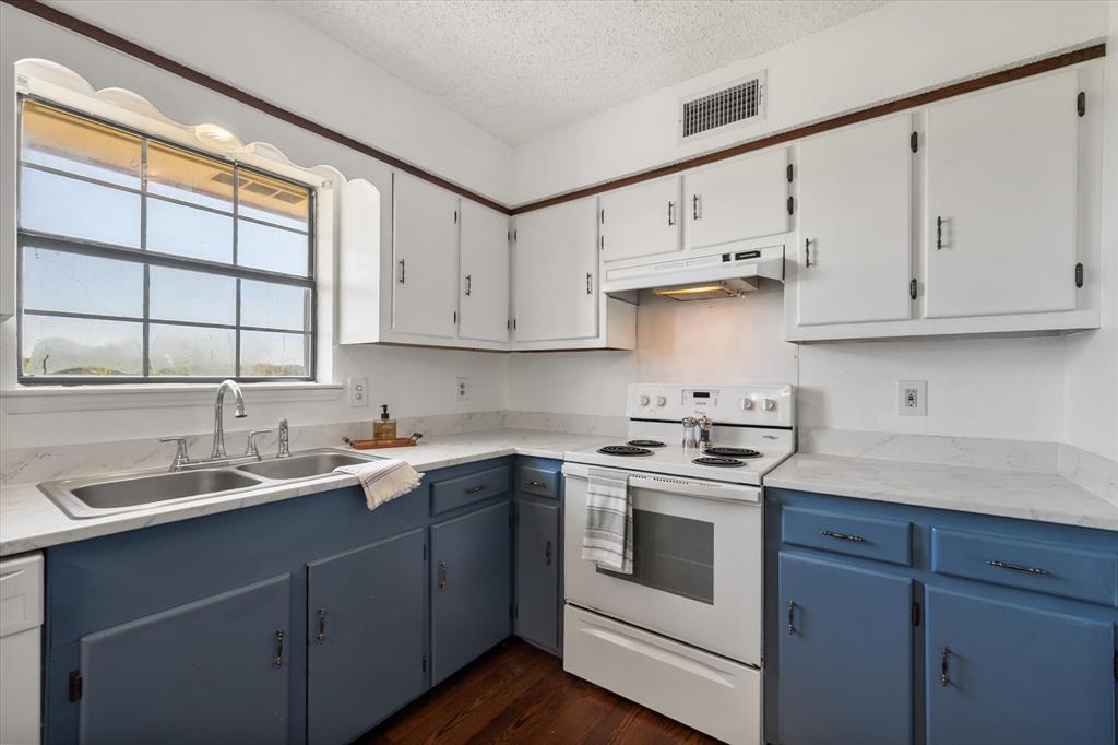 2038 Forreston Road Waxahachie, TX 75165 - Photo 11 of 39 Kitchen with white appliances, a textured ceiling, blue cabinetry, under cabinet range hood, and dark wood-style flooring