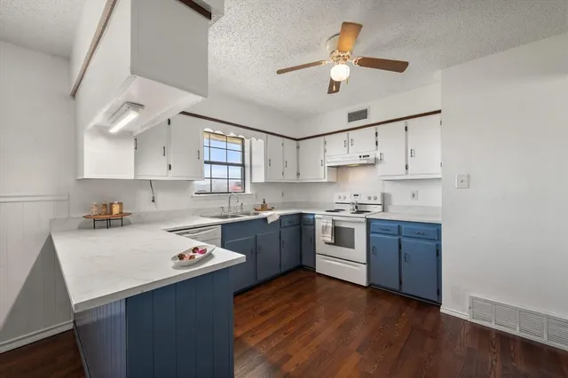 a kitchen with granite countertop a sink cabinets and wooden floor