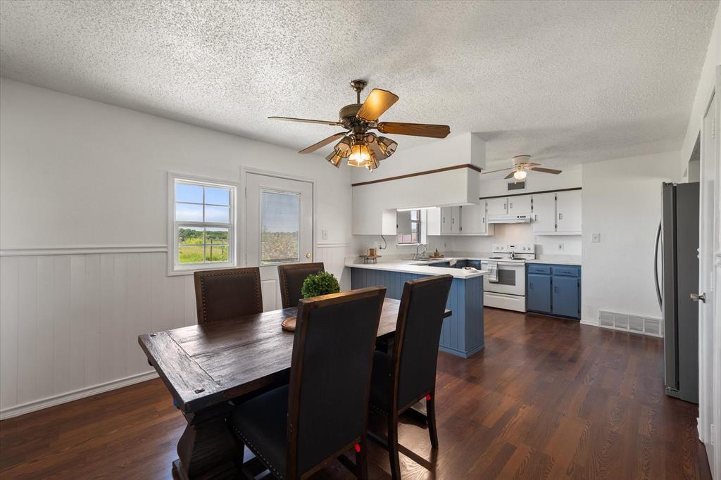 2038 Forreston Road Waxahachie, TX 75165 - Photo 15 of 39 Dining room with a textured ceiling, dark wood finished floors, ceiling fan, and wainscoting