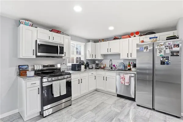 a kitchen with granite countertop a white stove top oven and refrigerator