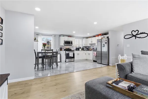 a living room with furniture and kitchen view with wooden floor