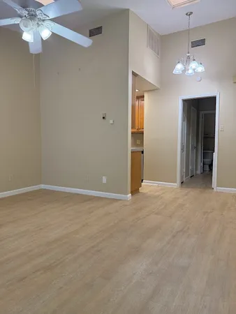 a view of an empty room with a chandelier fan