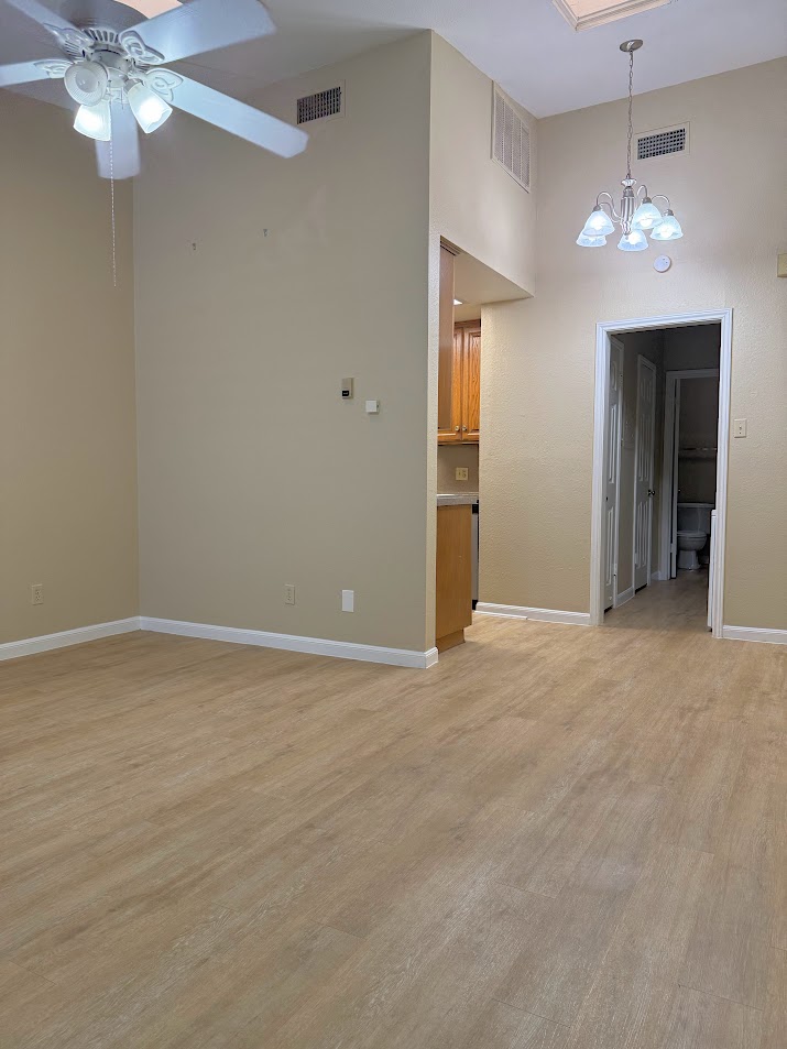 2529 Rio Grande Street, Unit 96 Austin, TX 78705 - Photo 2 of 11 Unfurnished room featuring a chandelier, a ceiling fan, baseboards, light wood-style flooring, and a towering ceiling
