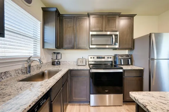 a kitchen with stainless steel appliances granite countertop a sink stove and refrigerator