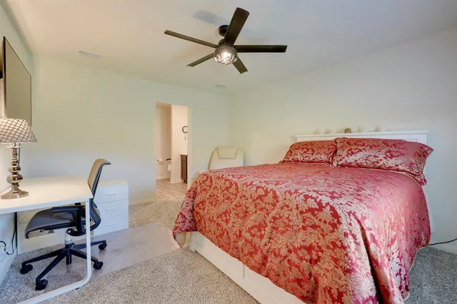 a bedroom with a bed a desk and chair with rug