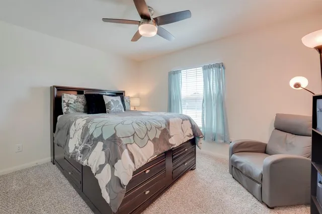 a bed room with a bed a couch and a ceiling fan