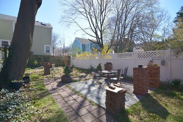 a view of a patio with table and chairs couches fire pit and large trees