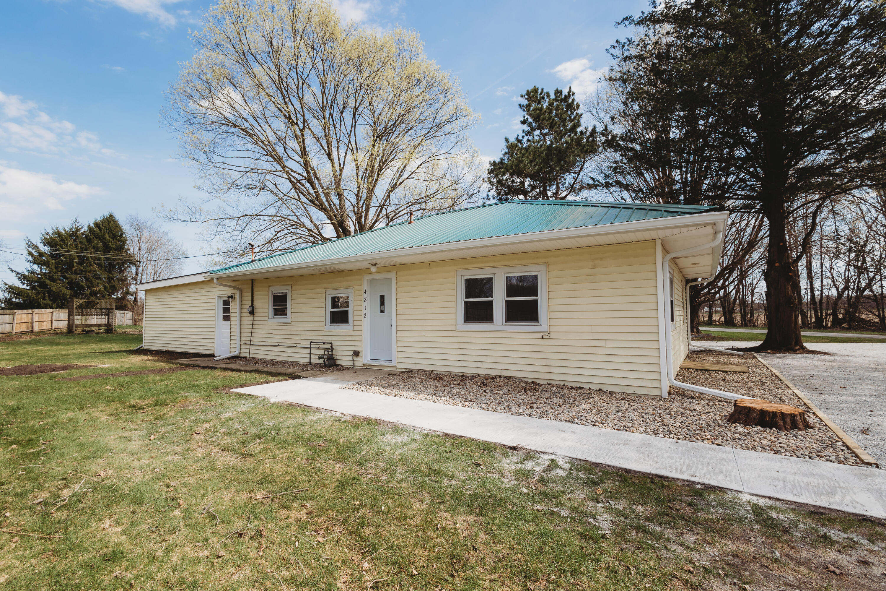 4812 East Bootjack Road Rolling Prairie, IN 46371 - Photo 1 of 13 a backyard of a house with large trees and brick walls