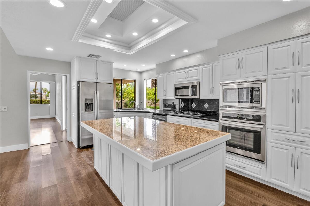 a large kitchen with stainless steel appliances granite countertop a lot of counter space and wooden floor