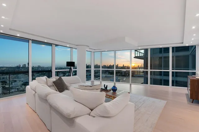 a living room with furniture large windows and a floor to ceiling window