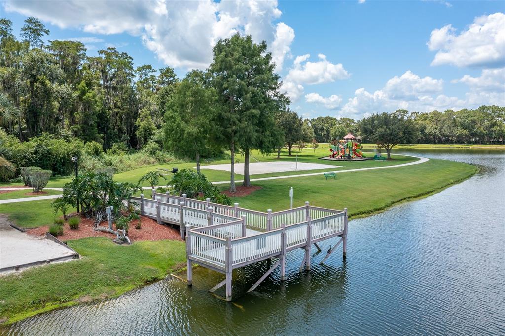 1017 Park Ridge Circle Kissimmee, FL 34746 - Photo 50 of 52 a view of a lake with a garden and a bench