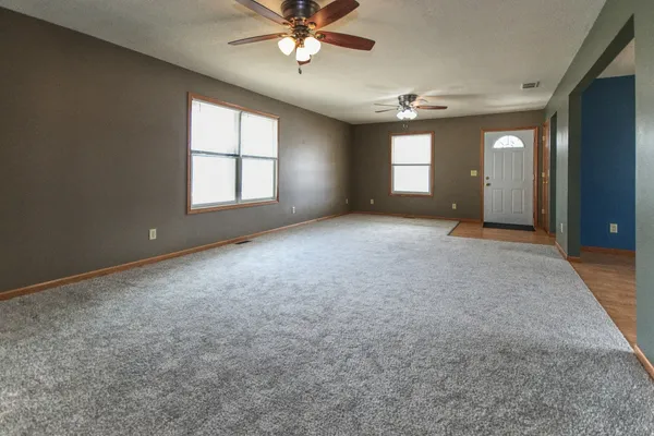 an empty room with windows and fan chandelier