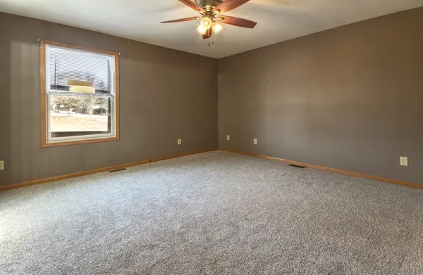an empty room with windows and fan