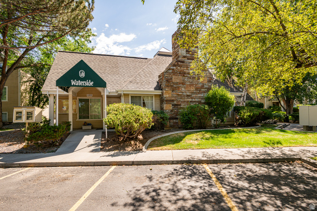 1221 Waterside Cove, Unit 11 Midvale, UT 84047 - Photo 21 of 23 Waterside building featuring a gabled roof, stone chimney, and a green fabric awning