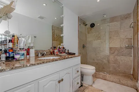 a bathroom with a granite countertop sink a toilet and shower