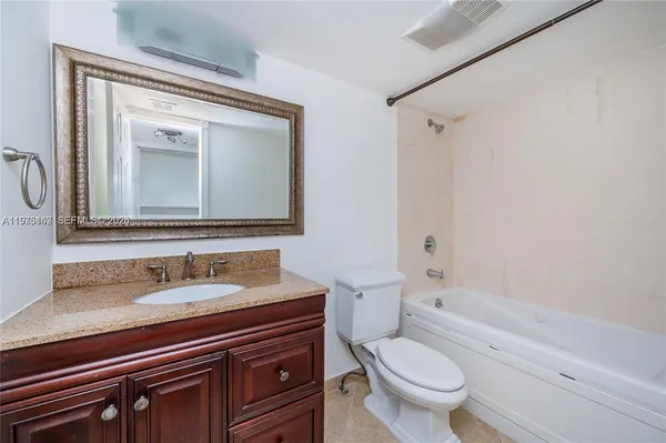 a bathroom with a granite countertop toilet sink and mirror