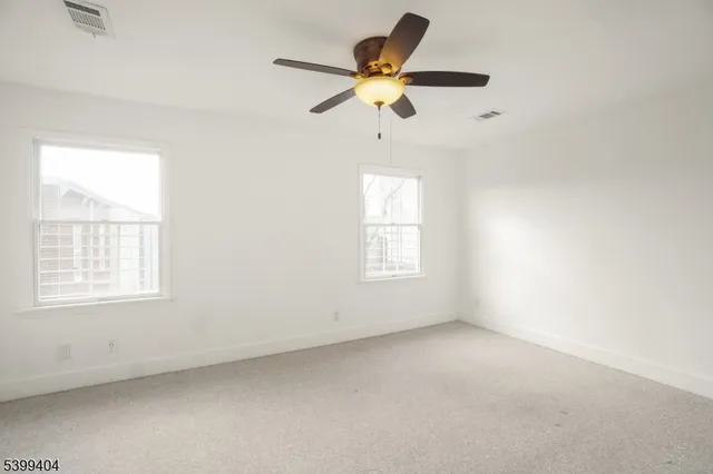 an empty room with a window and a fan