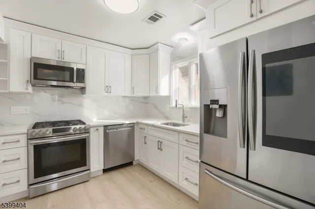 a kitchen with white cabinets stainless steel appliances and sink