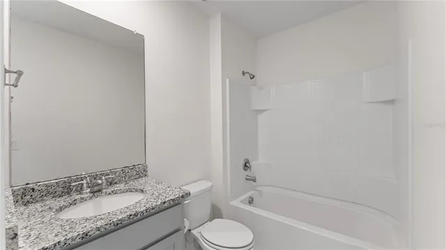 a bathroom with a granite countertop tub sink and mirror