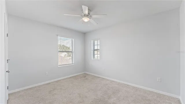 an empty room with windows and ceiling fan