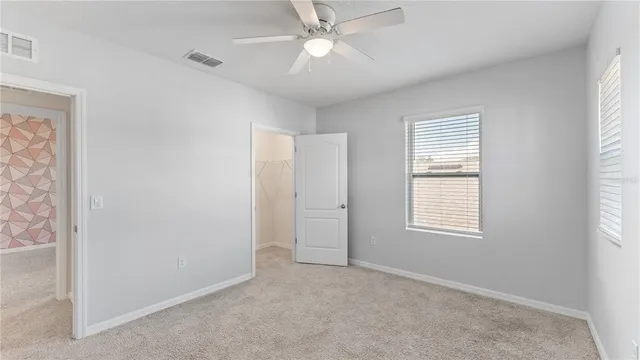 an empty room with windows and fan