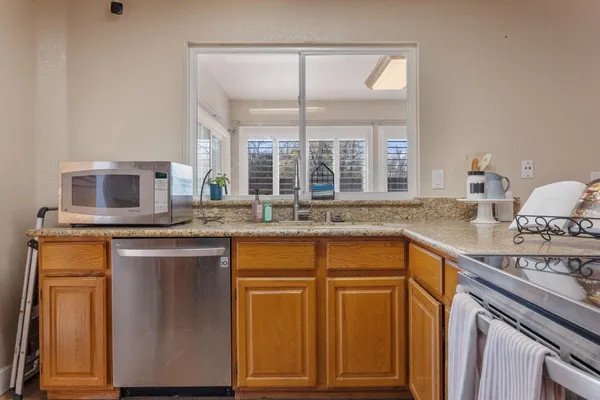 a kitchen with stainless steel appliances granite countertop a sink and a stove next to a window
