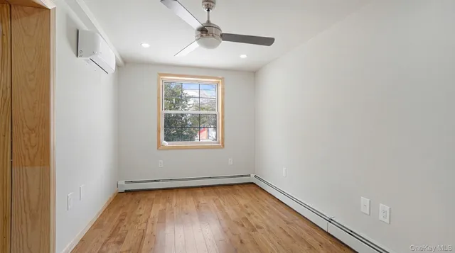 an empty room with wooden floor chandelier fan and windows
