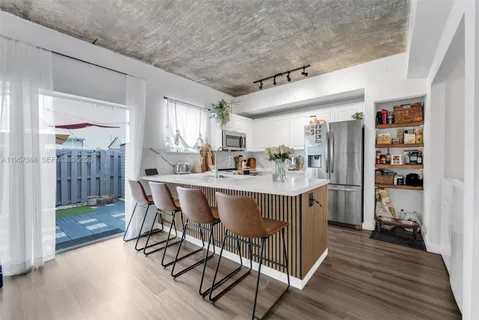 a kitchen with stainless steel appliances granite countertop a table chairs sink and cabinets