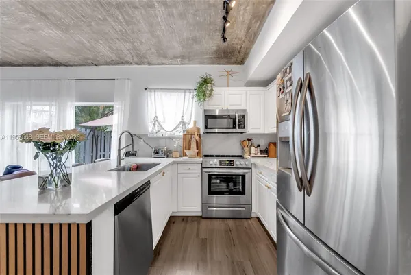 a kitchen with stainless steel appliances a sink a stove a refrigerator cabinets a dining table and chairs