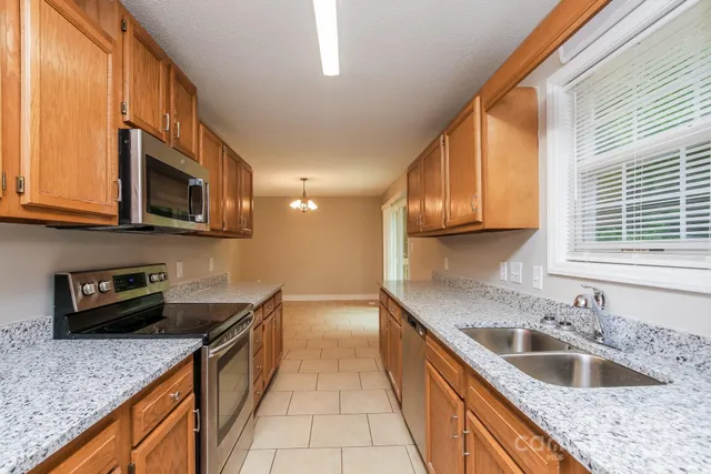 a kitchen with stainless steel appliances granite countertop a sink a stove top oven a counter space and cabinets
