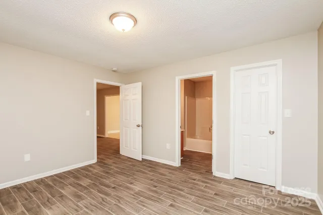 a view of an empty room with wooden floor and closet