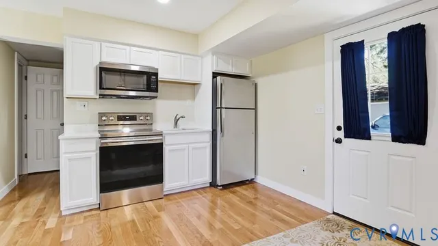 a kitchen with a refrigerator stove and wooden floor