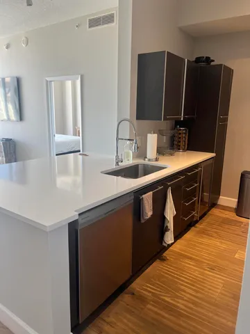 a kitchen with stainless steel appliances granite countertop a sink dishwasher and a refrigerator with wooden floor