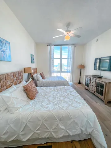 a bedroom with a bed a couch and a flat tv screen on the dresser