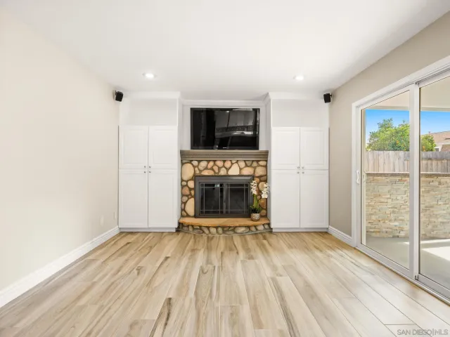 a view of a livingroom with wooden floor a flat screen tv and a fireplace