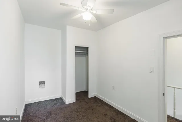an empty room with a ceiling fan and carpet