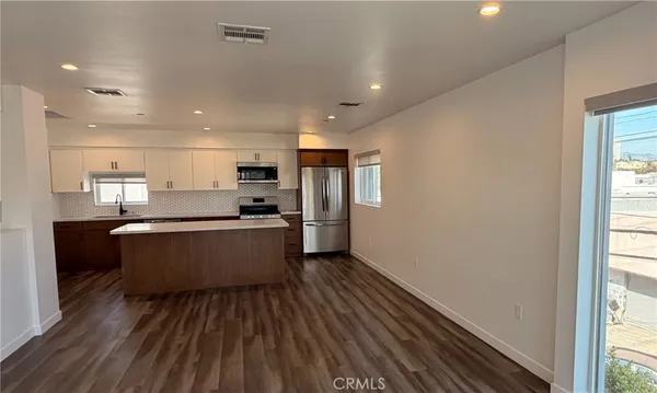 a large kitchen with stainless steel appliances kitchen island a large counter top and a wooden floors