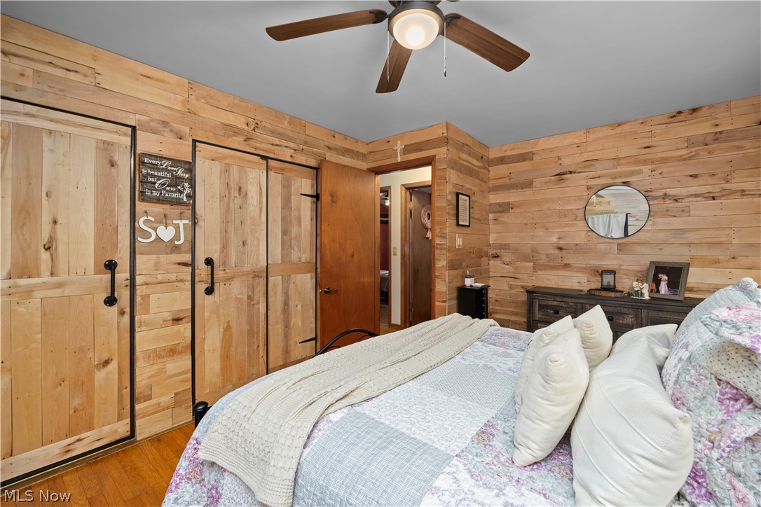 965 Gulf Road Elyria, OH 44035 - Photo 17 of 37 Bedroom with wooden walls, a ceiling fan, hardwood finished floors, and two closets