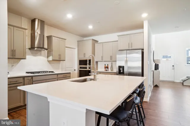 a kitchen with stainless steel appliances a stove a refrigerator white cabinets and wooden floor